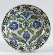 PLAT Creux en faïence à décor floral bleu, bordure décorée de spirales. Fracturé, recollé. Diam. : 35 cm. IZNIK, XVIème siècle