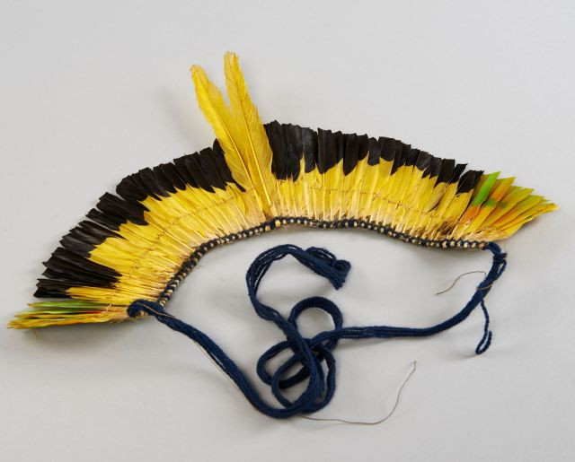 COIFFE en plumes jaunes et noires au recto et vertes au verso. Amazone aourou, cacique à dos jaune et cacique huppé. Haut. : 18 cm,...