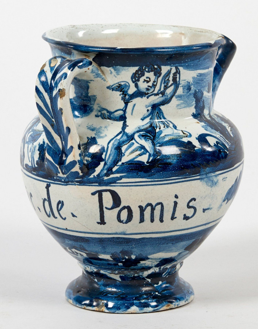 CHEVRETTE à décor bleu avec angelots et paysage, cartouche avec inscription "Syr.de.Pomis.". Haut.: 18,7 cm. Eclat au col. SAVONE,...