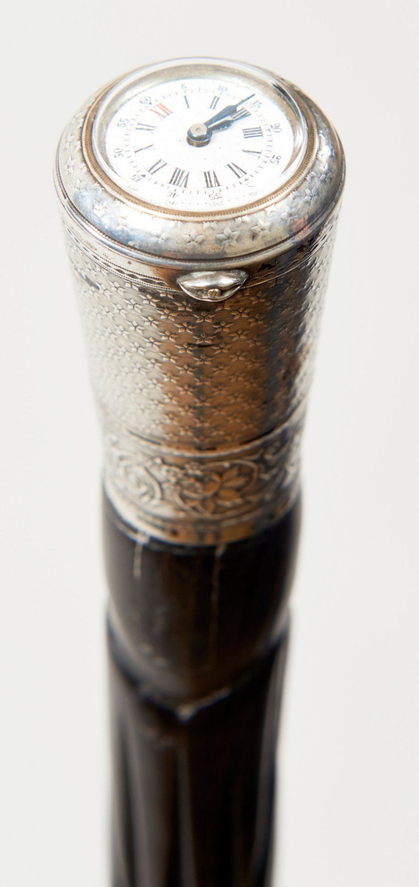 CANNE MONTRE, cadran émaillé blanc à chiffres romains et arabes inséré dans un pommeau en argent ciselé de guirlandes fleuries. Fût...