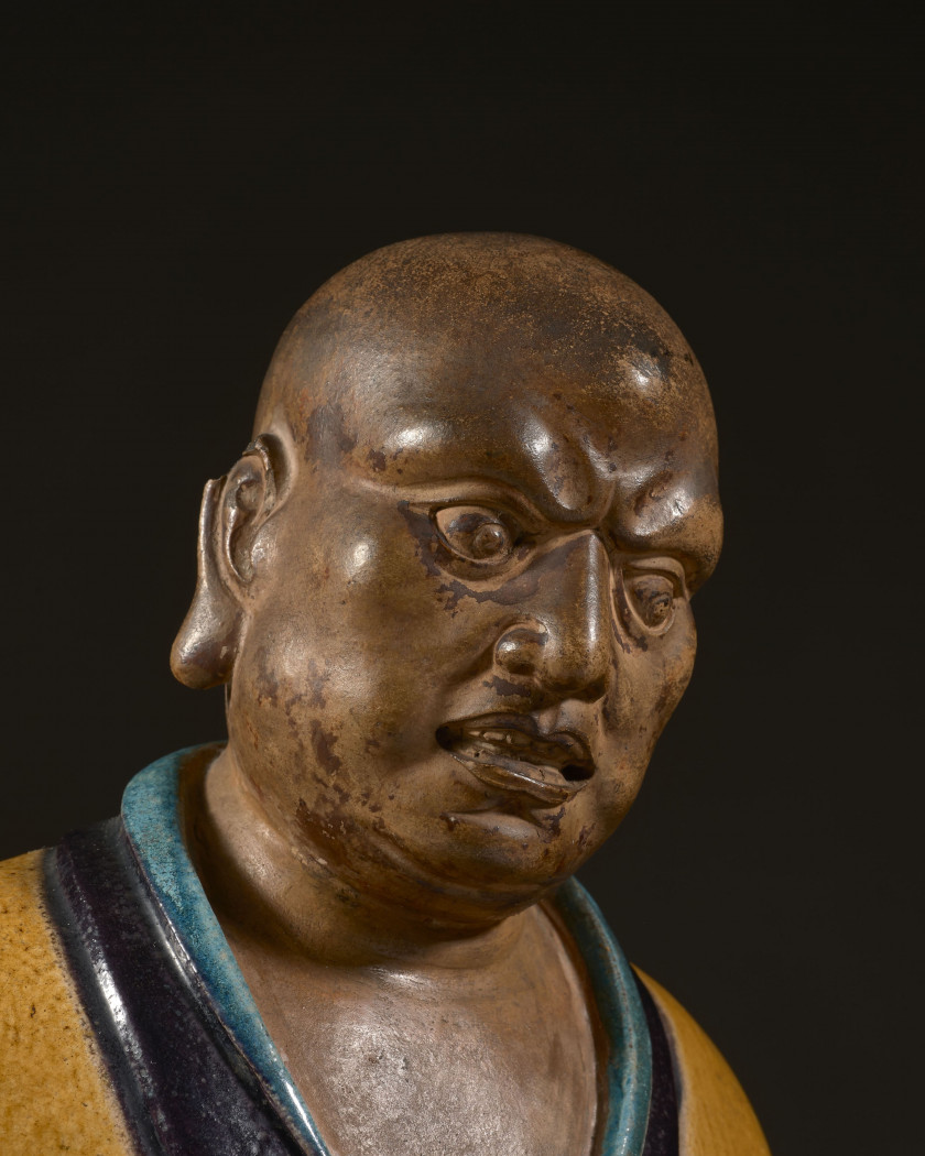 IMPORTANTE STATUE DE LUOHAN EN GRÈS ÉMAILLÉ JAUNE, TURQUOISE ET AUBERGINE, Chine, dynastie Ming (1368-1644)